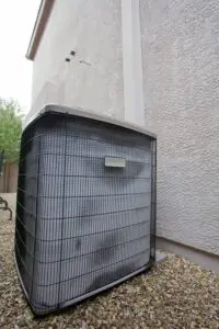 Air conditioning unit in the side yard of a home alongside wall