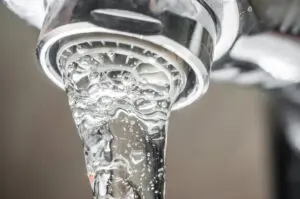 A sink faucet pours water through a reverse osmosis system installed by Day & Night