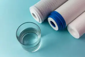 different types of filters sit next to a glass of water as Day & Night Air explain the benefits of installing water filters in your home