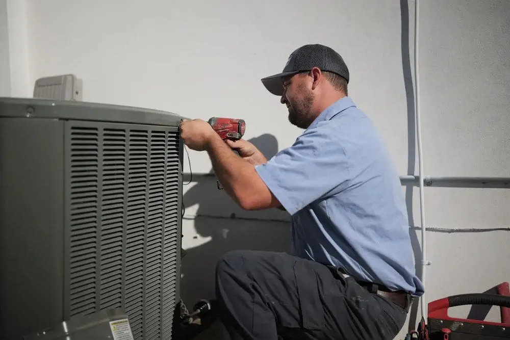 Commercial air conditioning unit undergoing maintenance in Phoenix, Arizona, positioned next to a building wall with visible tools used for servicing. Day & Night Air Conditioning, Heating, and Plumbing provides commercial AC maintenance in Phoenix, helping businesses maintain system performance through inspections and routine care. The scene highlights real HVAC maintenance work including panel adjustments, system checks, and equipment servicing for long-term operation. Businesses in Phoenix can contact Day & Night Air Conditioning, Heating, and Plumbing at (602) 584-7758 for commercial AC maintenance, repair, and installation services.