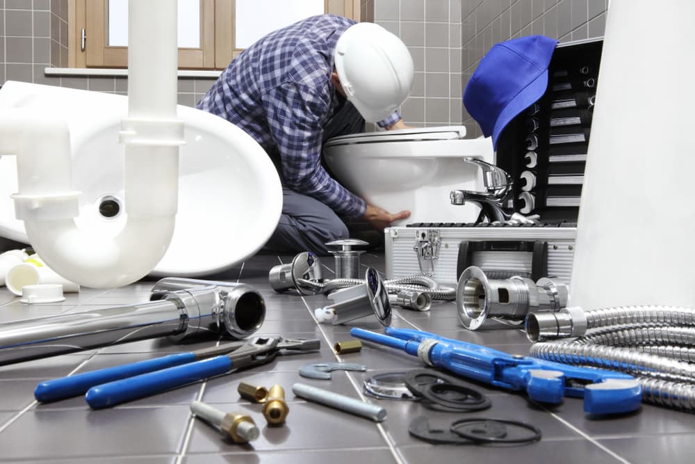 plumbing tools and a man repairing a bathroom toilet